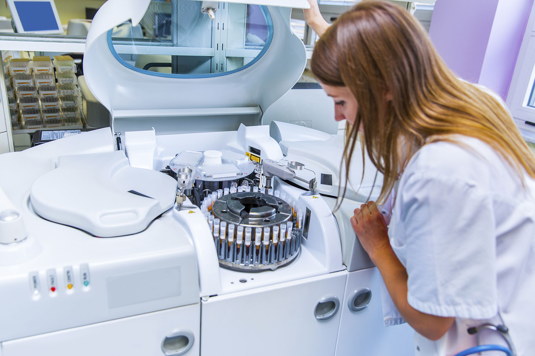 Young Woman Lab scientist placing test tubes with blood samples in a centrifuge